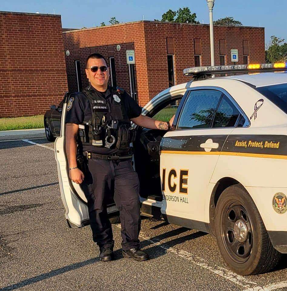 Officer and seminar instructor David Ortiz standing next to his police cruiser outside the police station.